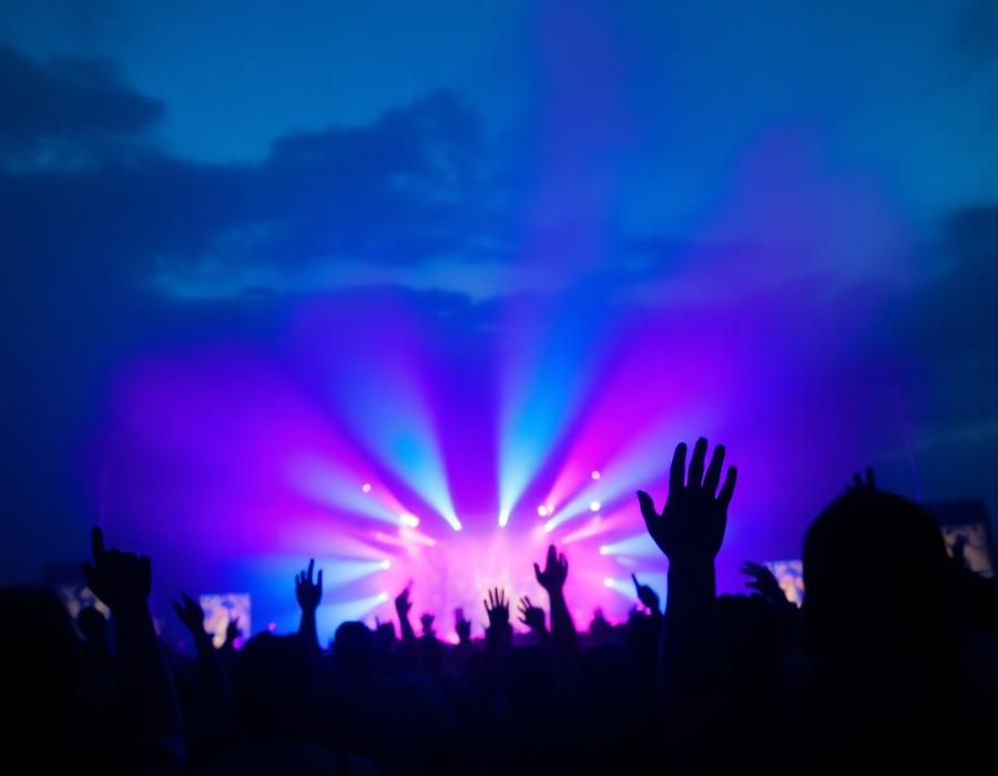 Festival crowd with hands raised under stage light